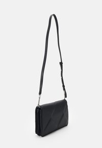 Svart crossbody-väska i texturerat material med en kviltad design, utrustad med en lång justerbar rem och silverkedjeaccenter.