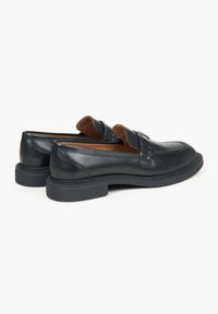 Black leather loafers with textured detailing, a rounded toe, and a contrasting dark sole. Inside features a smooth brown lining.