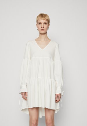 White cotton dress with a V-neck, long balloon sleeves, and a tiered skirt. Features gathered accents at sleeves with ties.