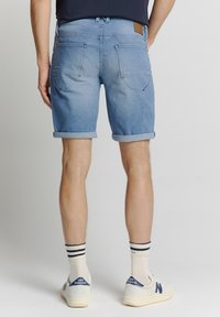 Leren denim shorts in lichtblauw, met opgerolde zomen, twee achterzakken en een bruine leren label op de tailleband.