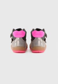 Gray and black sneakers with pink suede accents, a shiny textured back, and a rubber sole featuring a bright pink outsole. Velcro strap closure.