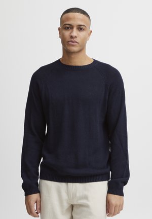 Navy blue knit sweater with long sleeves, round neckline, and ribbed cuffs and hem. Smooth texture with a fitted design and raglan sleeves.