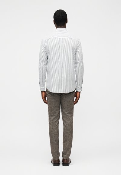 Camisa de botões às riscas com gola, combinada com calças cinzentas texturizadas e sapatos castanhos, vista de costas.