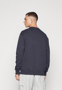 Sweatshirt marine à col et bas en côte, avec des manches longues et une coupe décontractée. Design simple, fabriqué en tissu doux.