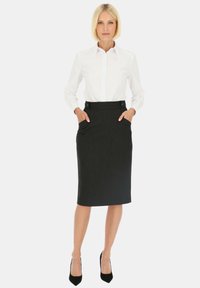 Biała koszula z guzikami w komplecie z czarną spódnicą ołówkową do kolan z bocznymi kieszeniami i dwoma guzikami zdobionymi w pasie.