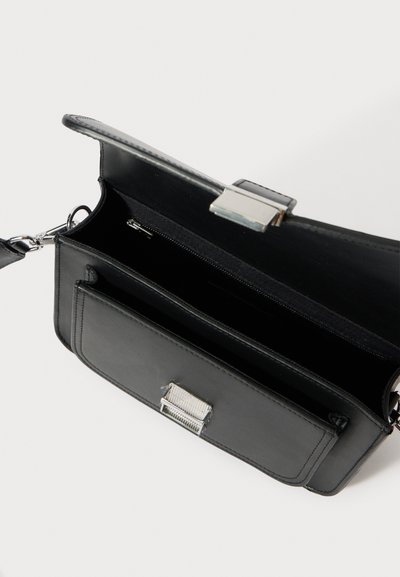 Melns ādas rokas soma ar gludu dizainu. Aprīkota ar sudraba aizdari, iekšējo rāvējslēdzēja kabatu un gludu tekstūru. Kompakta un funkcionāla.