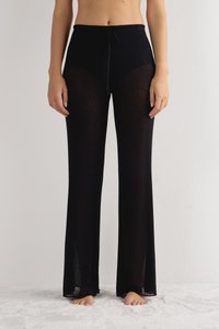 Zwarte gebreide wijde broek met een getextureerde afwerking, voorzien van een trekkoord in de taille en transparante panelen langs de benen. Zacht, lichtgewicht materiaal.