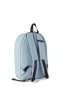 Mochila de tela azul claro con correas acolchadas, detalles negros, asa superior y un diseño elegante y redondeado. Presenta costuras visibles.