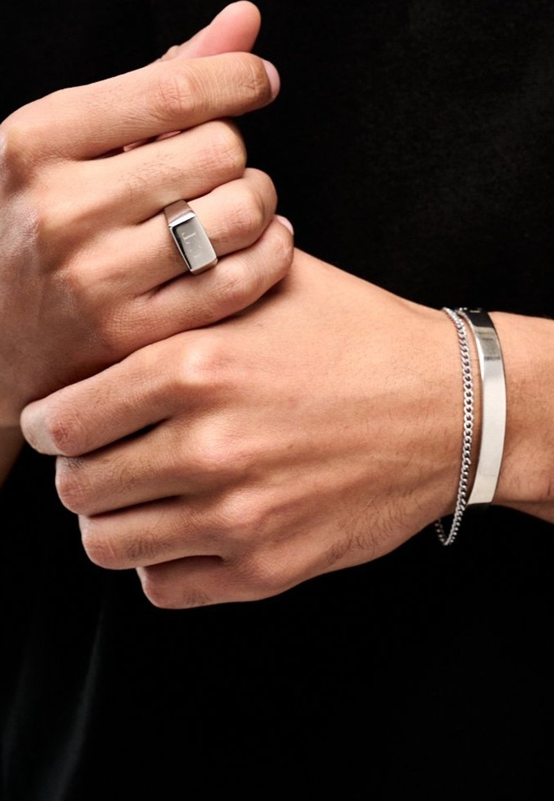 Sølv metallring med rektangulært topp og glatt overflate, kombinert med et sølvkjede-armbånd og et flatt bangles-armbånd.