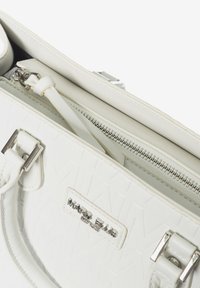 Borsa bianca texturizzata con chiusura a zip, hardware argentato, doppio manico corto e una placca con logo Marc Ellis sulla parte esterna.