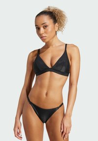 Svart bikini-set med ribbad textur. Toppen har en triangulär form med tunna justerbara band, och underdelen är lågrisk med smala sidor.