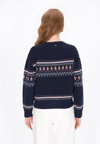 Pulover tricotat bleumarin cu un yoke decorat cu modele geometrice roșii, albe și albastre. Mâneci și tiv cu rețea, decolteu rotund.