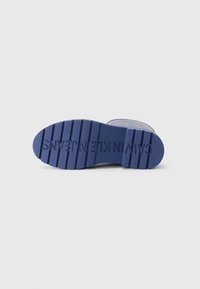 Semelle de botte en caoutchouc bleue avec des rainures horizontales, comportant un nom de marque en relief et une finition texturée pour une meilleure adhérence. Design minimaliste.