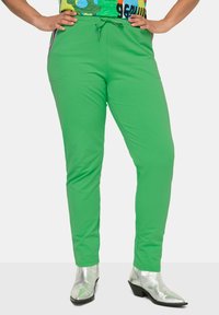 Groene katoenen joggerbroeken met een trekkoord in de taille, taps toelopende benen en zijstrepen. Gecombineerd met zilveren enkellaarsjes.
