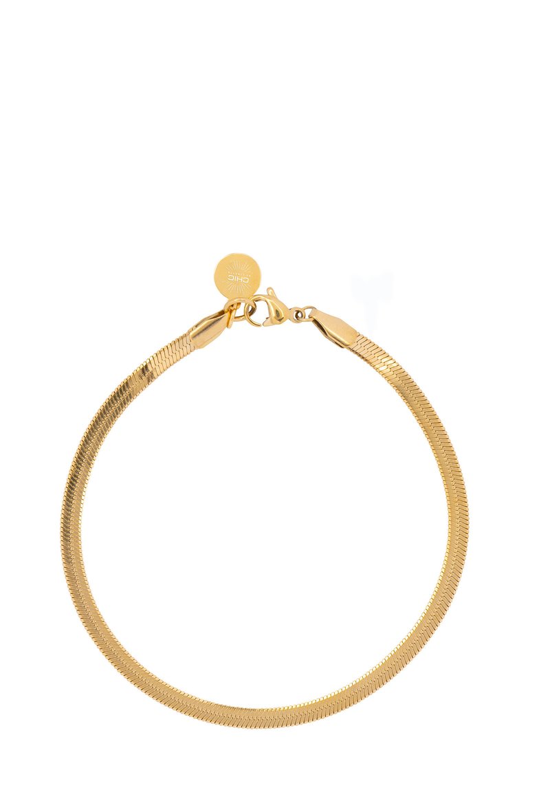 Pulsera de tono dorado con un diseño liso y flexible, que presenta un broche de langosta y una pequeña etiqueta redonda con un patrón de rayos de sol.