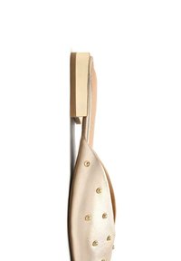 Zapato de cuero beige con una textura suave, que presenta remaches dorados redondos y una suela plana de color crema sólido. La vista lateral captura la forma del diseño.