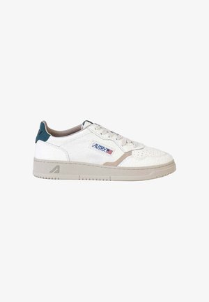 Baskets basses blanches avec semelle beige, bout perforé, patch bleu au talon et logo Autry avec drapeau américain sur le côté.