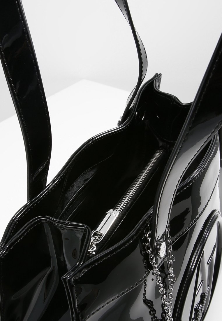 Svart patenterad läder tote väska med en glänsande yta, som har två långa handtag, en dragkedjeficka och en kedjeaccentdetalj.