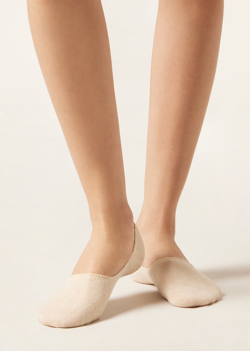 Calcetines beige sin ajuste con una textura suave, diseño de corte bajo y puntas redondeadas, que presentan un acabado sin costuras en los bordes.