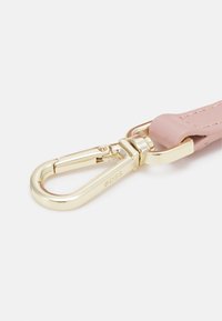 Fermoir en métal doré fixé à une sangle en cuir rose, avec "BOSS" gravé sur le fermoir.