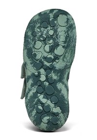Suola di scarpa in gomma verde con un motivo testurizzato e dinamico, caratterizzato da forme circolari di diverse dimensioni e un piccolo dettaglio di design giocoso.
