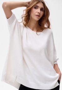 Witte oversized gebreide trui met geribde cuffs en zoom. Zachte textuur, ontspannen ontwerp en wijde mouwen. Geschikt voor casual kleding.