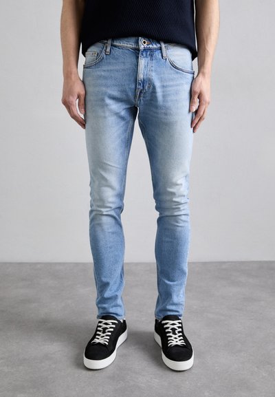 Jasnoniebieskie dżinsy, slim fit, z wyblakłym wykończeniem, klasyczny pięciopakowy design oraz kontrastowe stębnowanie. W połączeniu z czarnymi trampkami.