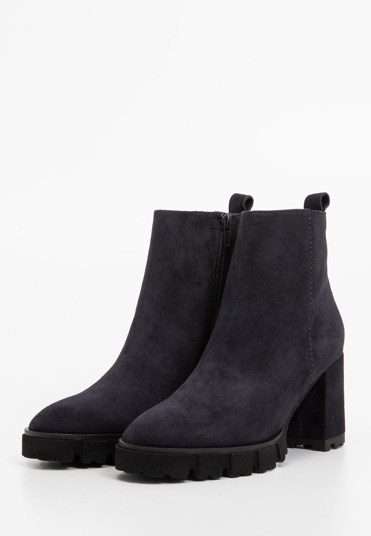 Schwarze Wildleder-Stiefeletten mit einem klobigen Absatz und einer strukturierten Gummisohle. Mit einem seitlichen Reißverschluss und einer glatten, matten Oberfläche.