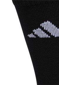 Zwarte sportieve sok met geribbeld patroon, voorzien van een wit logo op de buitenzijde, wat een moderne minimalistische stijl benadrukt.