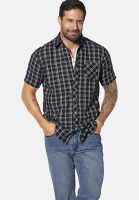 Kurzärmeliges kariertes Hemd in Marineblau und Hellblau, mit Knopfverschluss, einer Brusttasche und einem lockeren Schnitt, kombiniert mit blauen Jeans.