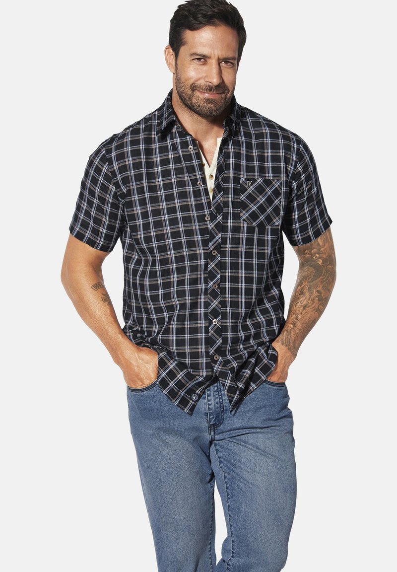 Kurzärmeliges kariertes Hemd in Marineblau und Hellblau, mit Knopfverschluss, einer Brusttasche und einem lockeren Schnitt, kombiniert mit blauen Jeans.