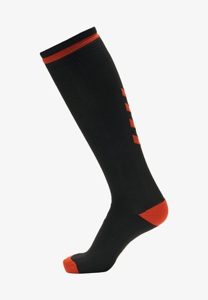Sorte knæhøje sokker med orange accenter, der har ribbet tekstur, kontrasterende tåkap og fem lodrette striber på siden.