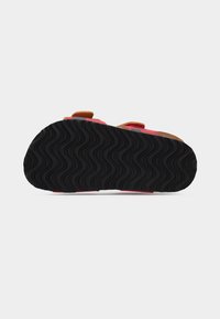 Παιδικά σανδάλια με μαύρη λαστιχένια σόλα, ροζ μαξιλαρωτό πάτο και καφέ συνθετικά λουριά. Διαθέτουν πέλμα με κυματιστό μοτίβο για πρόσφυση.