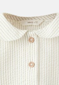 Svetla srajca z ovratnikom, ki ima navpične proge v zeleni in zlati barvi, z lesenimi gumbi in teksturirano tkanino. Primerna za dojenčke, stare od 6 do 9 mesecev.