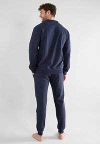 Navy blue cotton sweatshirt and matching joggers, featuring a relaxed fit, long sleeves, and ribbed cuffs and waistband. No visible patterns.