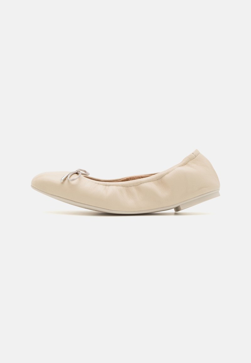 Ballerine en cuir beige avec un bout rond et un petit nœud sur le devant. La chaussure présente un talon légèrement surélevé et une texture plissée.