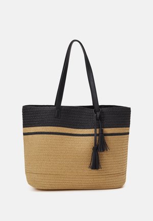 Bolsa tote con diseño de paja tejida en tonos marrón claro y negro, con asas negras y dos borlas negras colgando en el lateral.