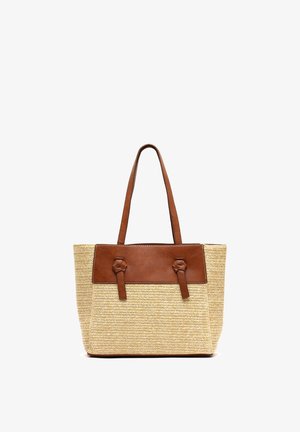 Beige geweven tote tas met bruine leren bies en lange bruine leren handvatten, rechtopstaand op een witte achtergrond.