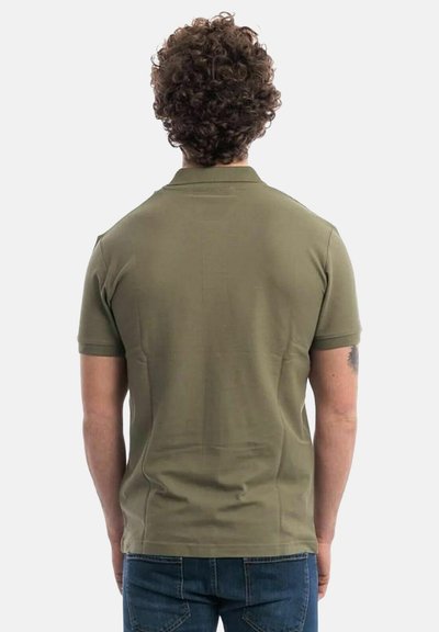 Polo di colore verde oliva con una texture morbida, maniche corte e colletto, mostrato da dietro, abbinato a jeans blu.