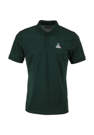 Camisa polo verde oscuro con cuello, tapeta de dos botones y mangas cortas. Presenta un pequeño logo en la zona del pecho izquierdo. Textura suave.