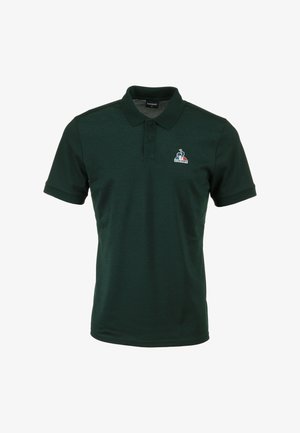 Polo shirt verde scuro con colletto, pattina con due bottoni e maniche corte. Presenta un piccolo logo sull'area del petto sinistro. Tessuto liscio.