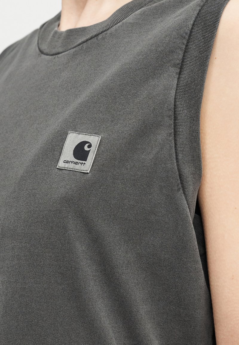 Close-up of a person wearing a dark gray sleeveless shirt with a Carhartt logo patch on the chest.