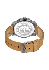 Timberland-klocka med ett fodral av rostfritt stål, en rem av tanläder och en rund urtavla med en cirkulär logotyp på baksidan.