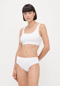 Valkoinen saumaton bralette ja siihen sopivat alushousut, jotka on valmistettu pehmeästä ja joustavasta materiaalista. Braletessa on neliön muotoinen kaula-auko; alushousuissa on leveä vyötärönauha.