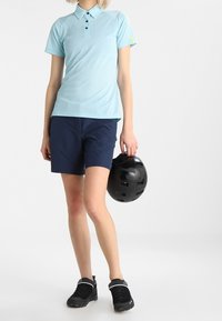 Světle modré polo tričko s krátkým rukávem, tmavě modré šortky, černé tenisky a černá helma. Hladký materiál a jednoduchý design.