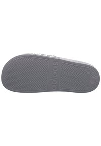 Adidasova potplat u sivoj gumi s teksturiranim ribljim kostima i utisnutim logotipom. Ima ravan dizajn za prianjanje i stabilnost.
