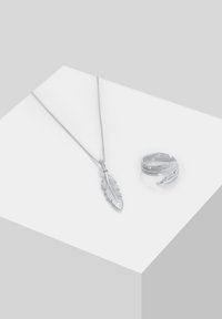 Sølvsmykke med en fjer vedhæng og en matchende ring med et blad design, begge har en poleret overflade og tekstureret detaljer.