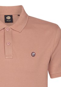 Polo tričko ve světle růžové barvě, vyrobené z texturované bavlny. Obsahuje límec, tříknoflíkovou légu a malé, kulaté černé logo na hrudi.