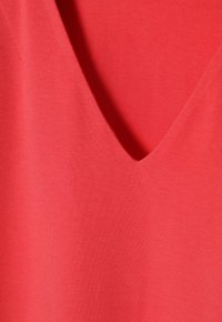 Rød V-hals top lavet af blødt bomuldsstof, med en glat tekstur og et rent, enkelt design uden yderligere mønstre eller accenter.