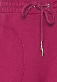 Fuchsia joggingbroeken met een elastische tailleband, voorzien van een trekkoord met metalen uiteinden en een zijzak, gemaakt van zachte stof.